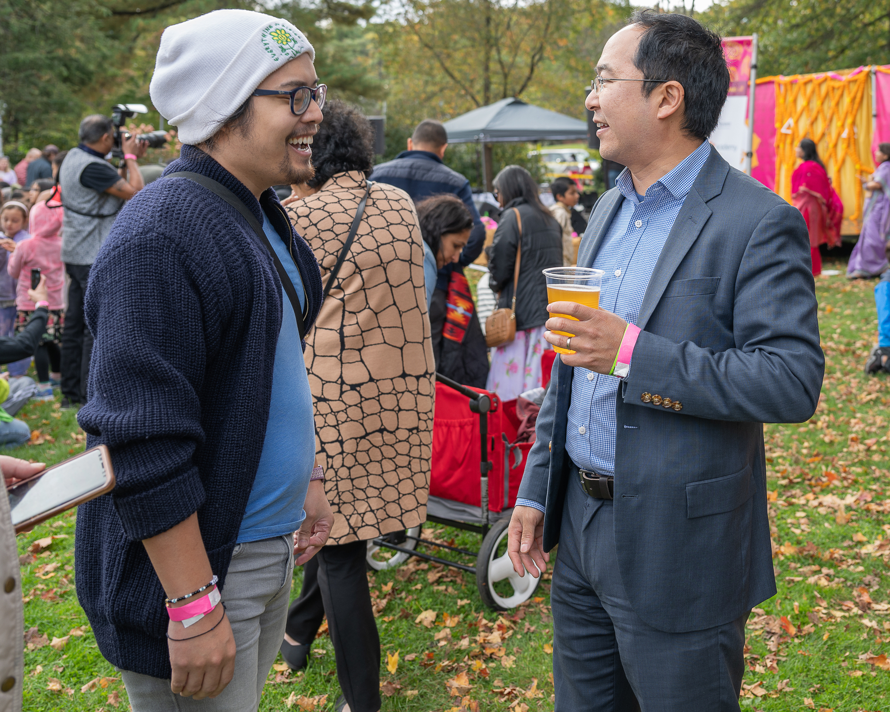 Miguel a masc Filipino man on the left talking with Andy Kim a congressman who is on the right. They are outdoors in the daytime in the fall. 