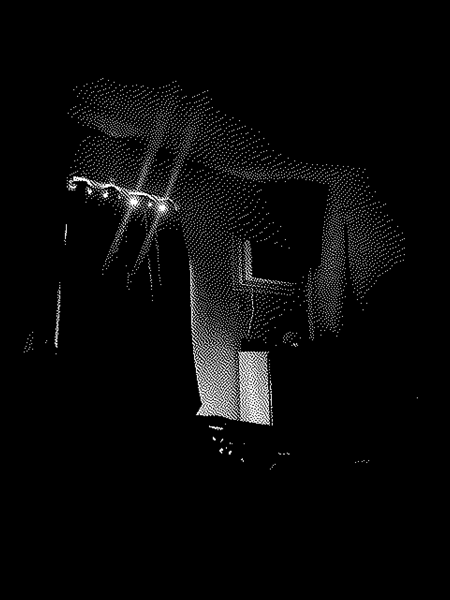 black and white 8 bit photo of a room. you can see sunlight streaming thru a closed curtain. light is touching a dresser and air conditioner. it is mostly dark.