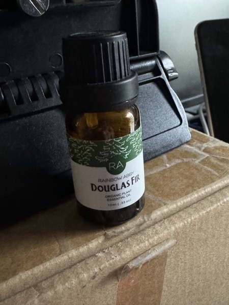 a close-up of a bottle of douglas fir scented essential oil sat on a cardboard box