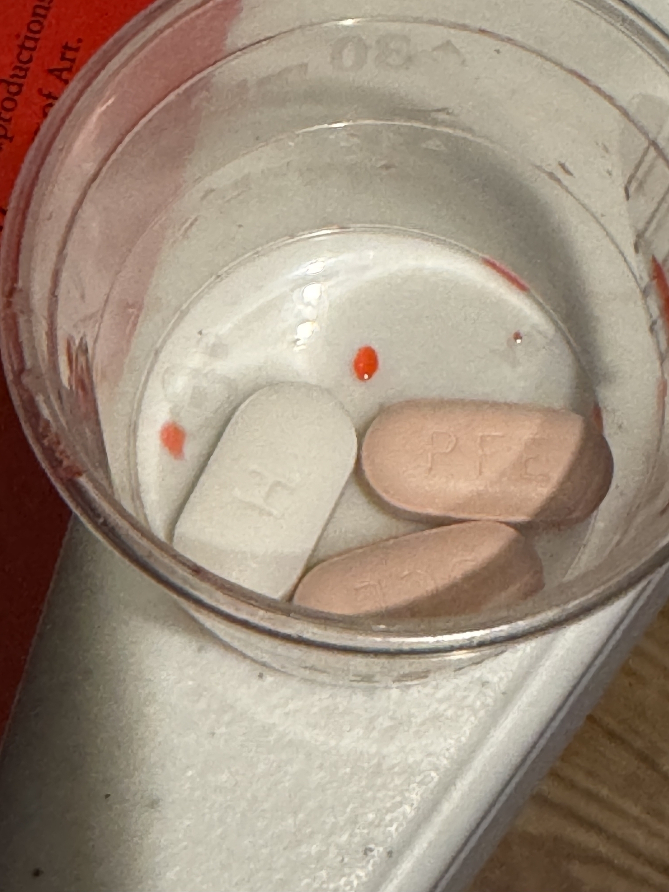 Prescription medicine tablets in a plastic cup.