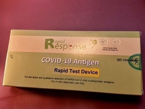 A COVID-19 antigen rapid test device box on a purple surface.