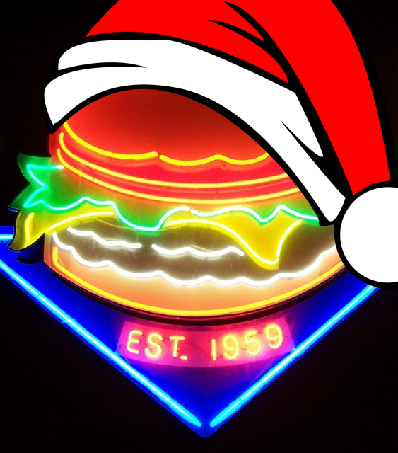 A neon sign of a cheeseburger wearing a red Santa hat.
