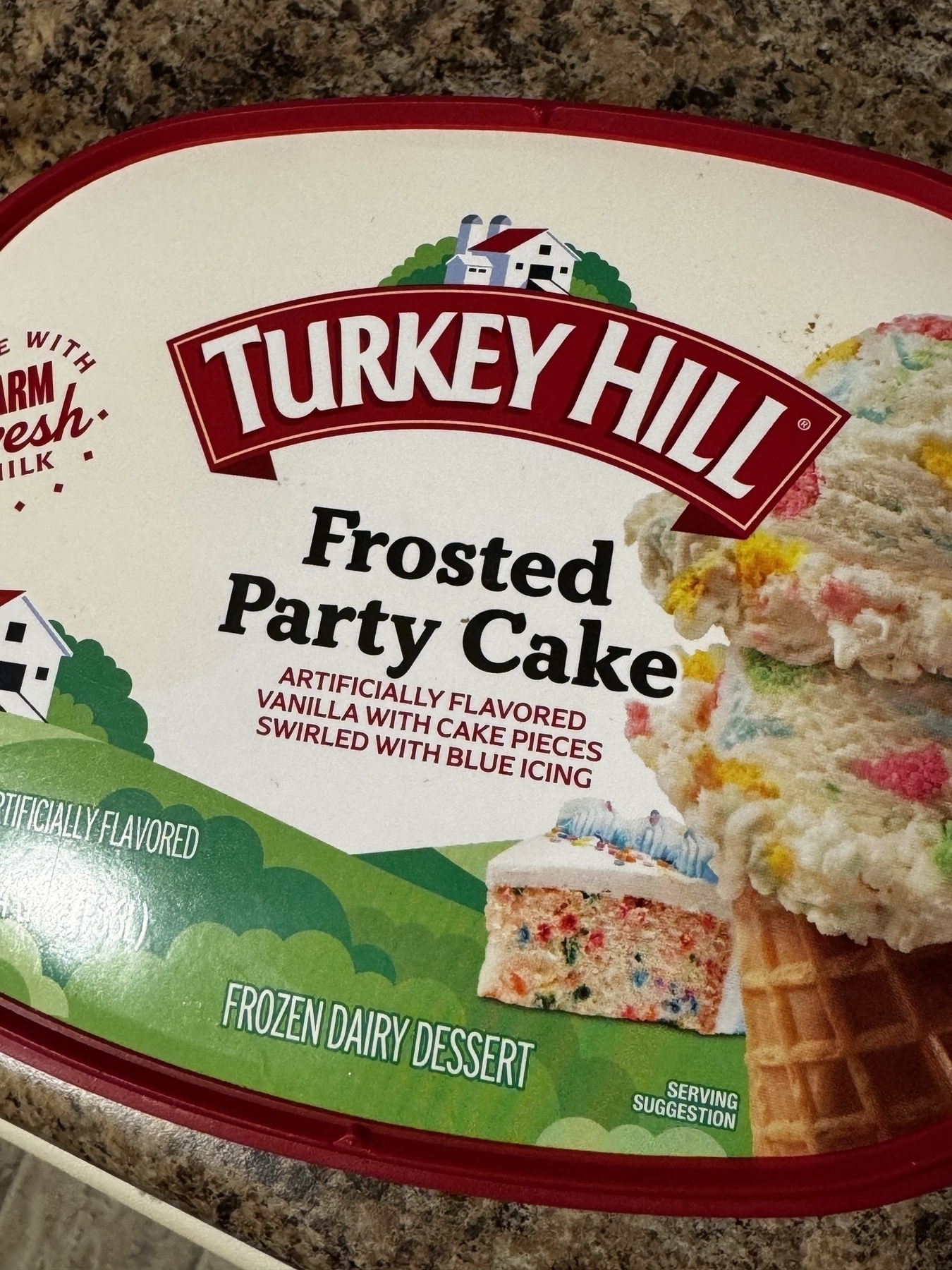 Container of Turkey Hill Frosted Party Cake flavored frozen dairy dessert with an image of the product on the label.