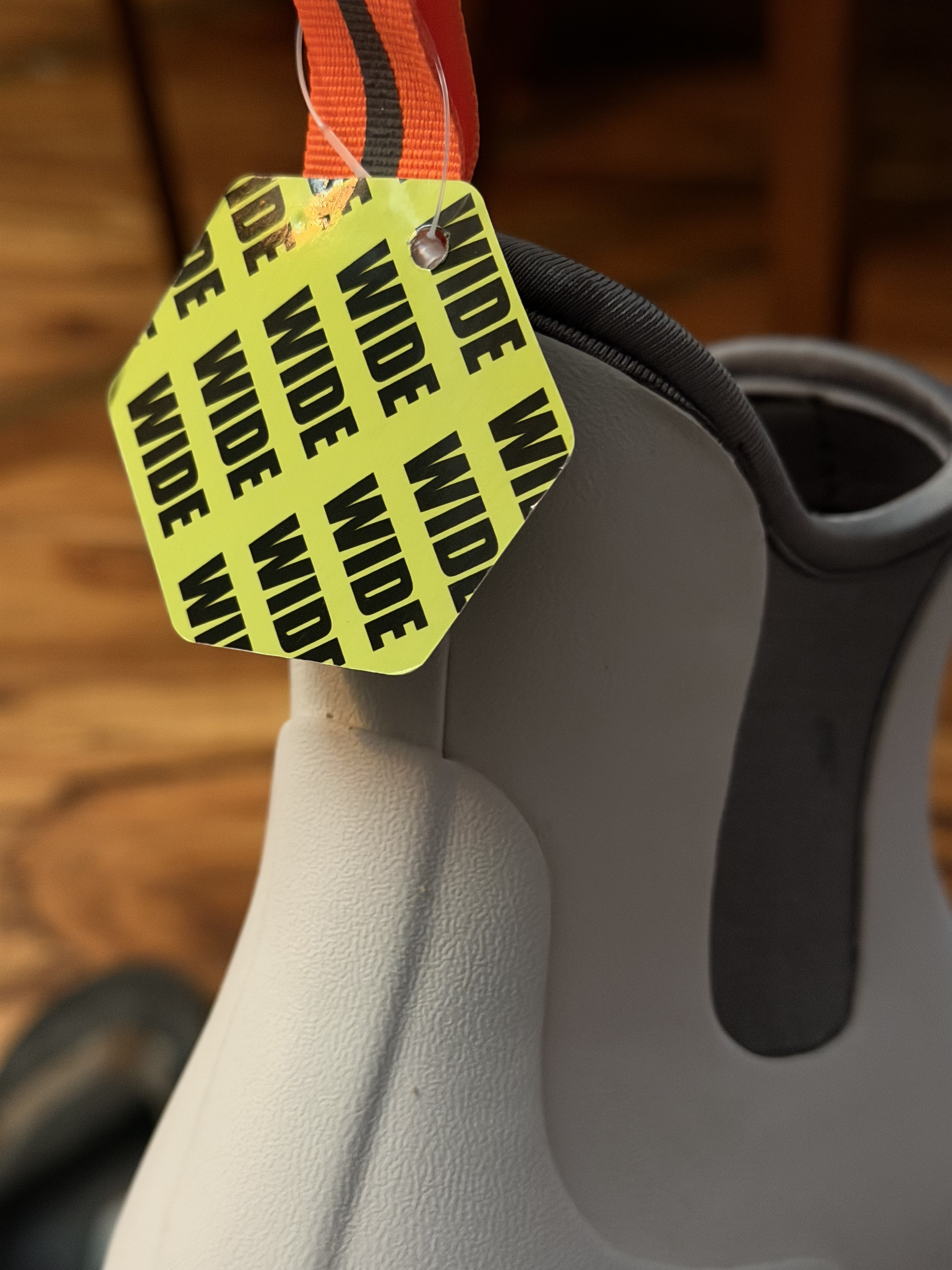 top of a white rainboot in close up. showing tag with yellow background that says wide over and over